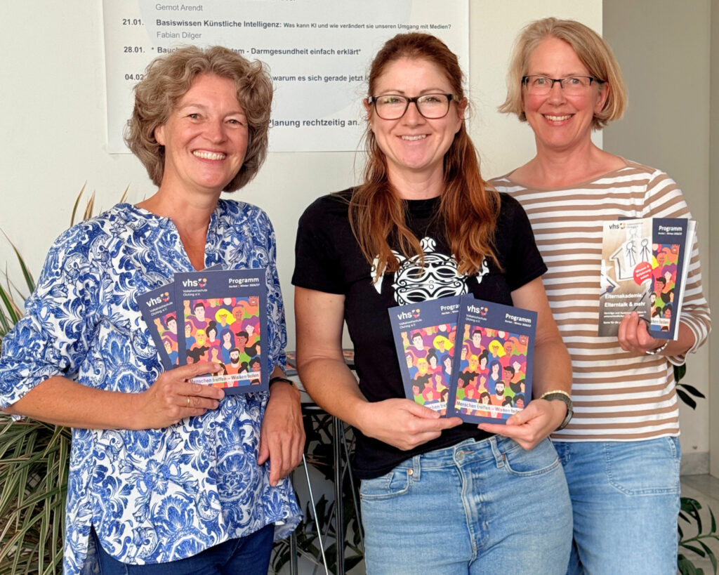 Drei Mitarbeiterinnen der vhs Olching halten das neue Programmheft in den Händen.